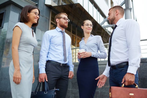 Group of young successful business people chatting outside modern office building during break